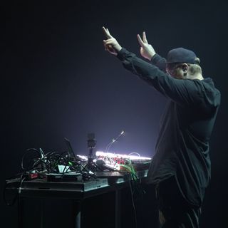 man giving the peace sign behind music gear